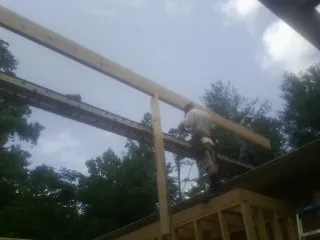 Carpenter setting a ridge beam over a new addition frame — Ice Dam Removal by Roofing Brothers in Avondale